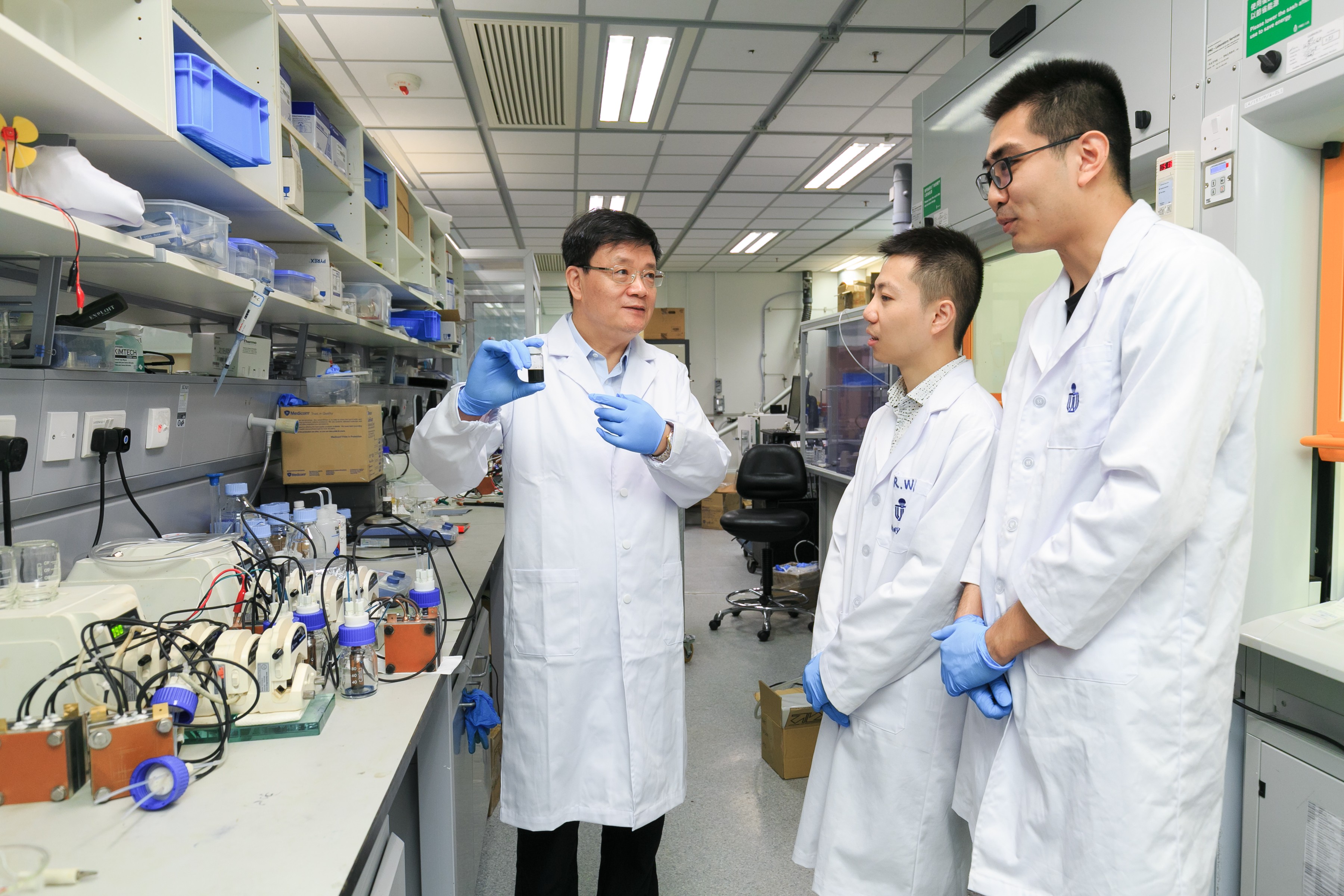 Prof. Zhao Tianshou (left) shows a sample of the e-fuel to his team members.