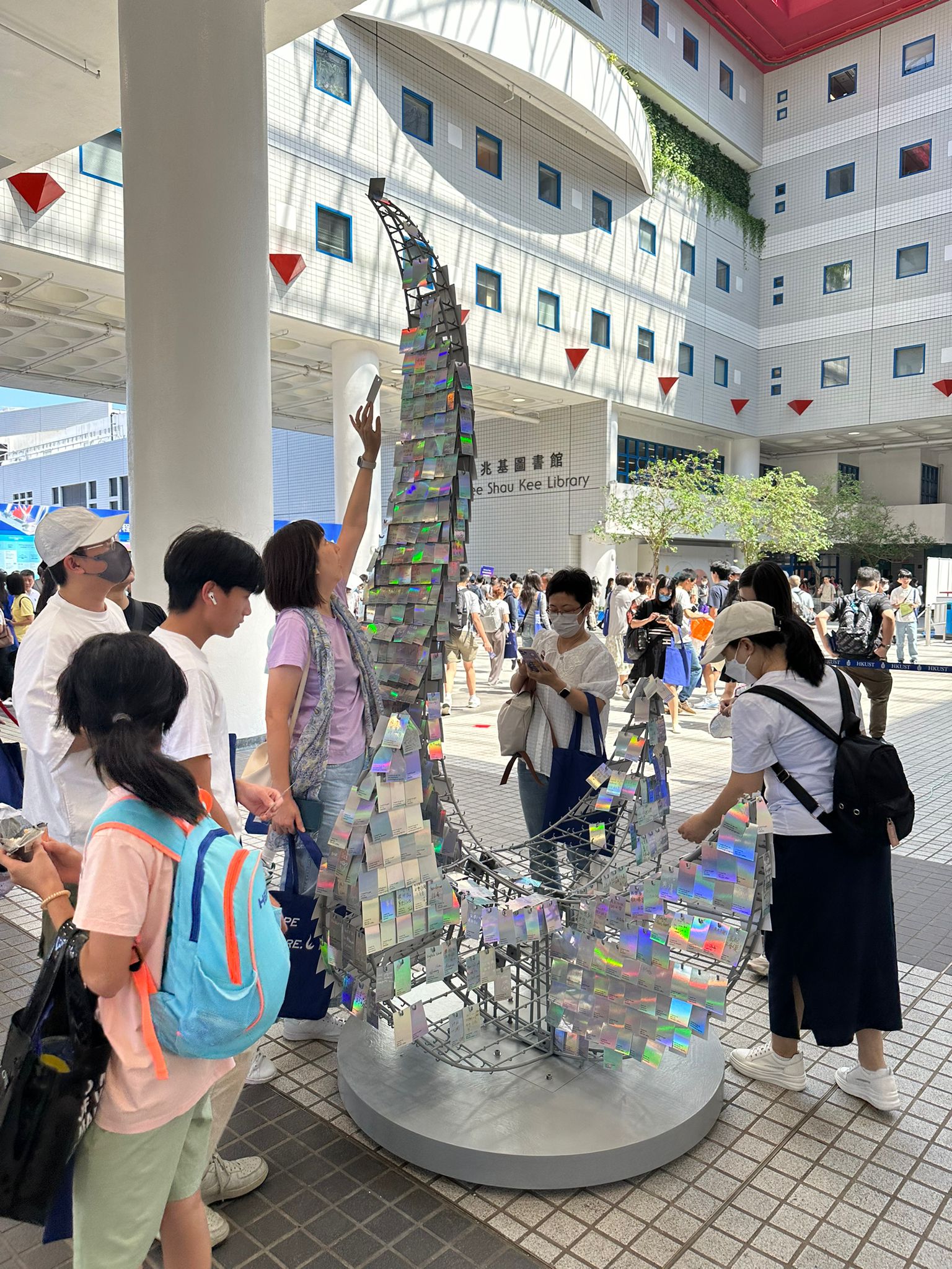 今年是科大在社會全面復常後舉辦的首個本科入學資訊日，校方邀請同學在卡紙寫上未來願景，並掛上特別設計的大型科大標誌 – 紅鳥日晷雕塑的模型擺設，象徵本年的主題「We Shape the Future（一起塑造未來）」。