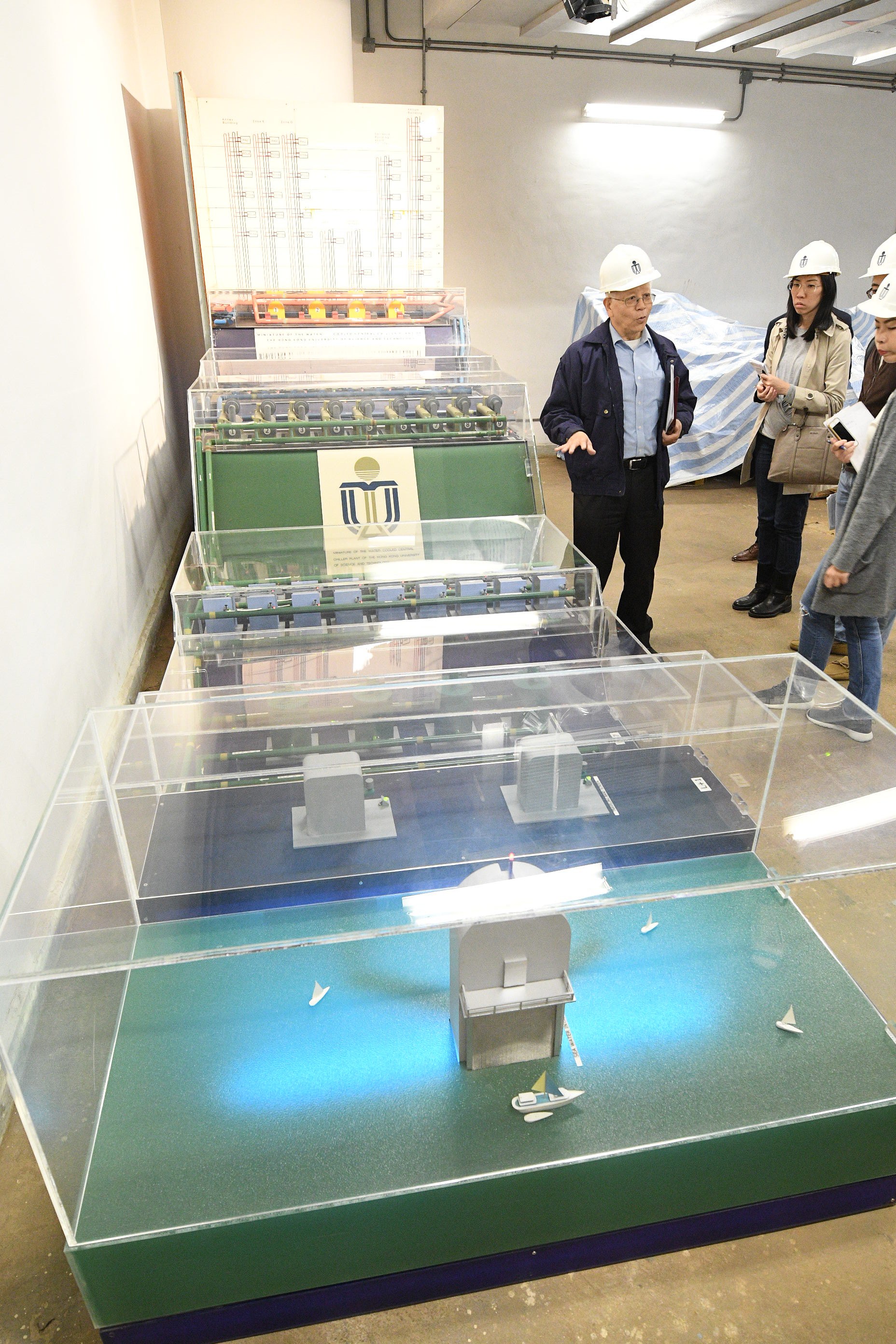  Lam (first left) introduces a model of the district cooling system to the media.