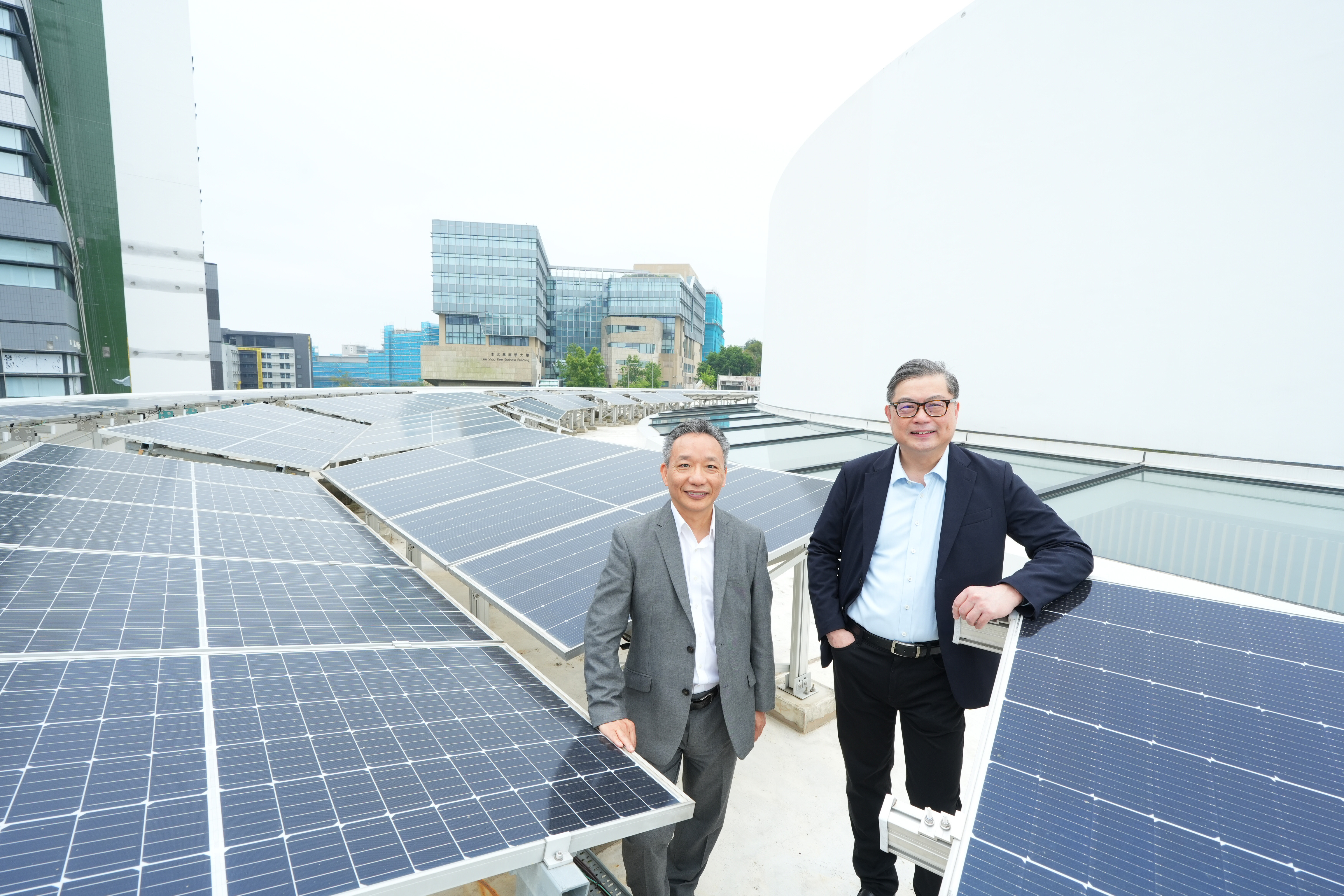 A group photo of Prof. TAM Kar-Yan (right), Vice-President for Administration and Business, and Dr. Kenneth LEUNG (left), Director of Sustainability/Net-Zero, showing the sizeable solar panel systems installed on the rooftop of Shaw Auditorium, which has  doubled the capacity of Hong Kong’s highest green building certification requirements. This illustrates a key component of the Action Plan - stringent design and operational guidelines for new and renovated buildings. 