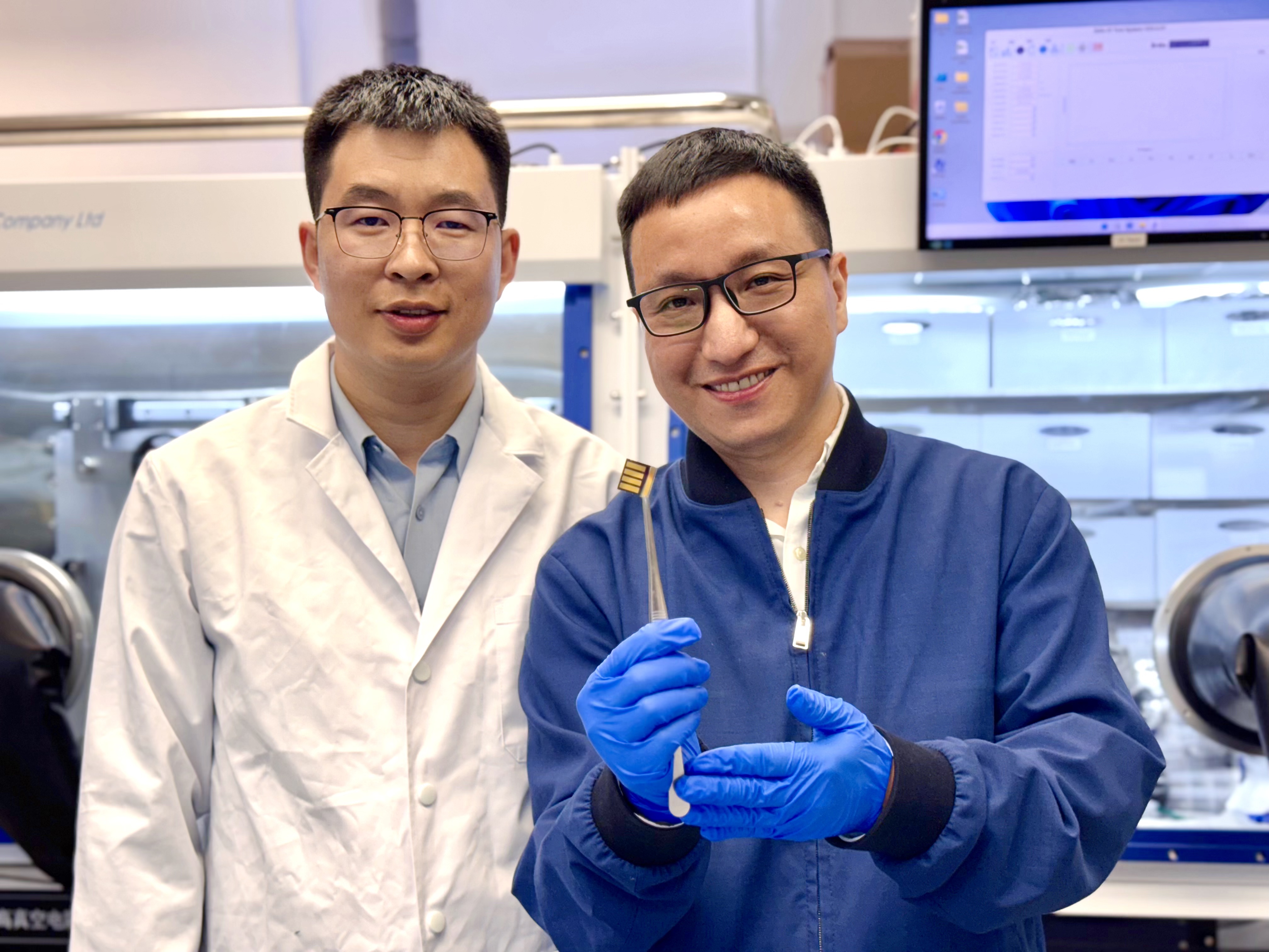 The lead corresponding author Prof. Zhou Yuanyuan (right) and co-first author Dr. Guo Pengfei (left) are showing a perovskite solar cell prototype made for a proof-of-concept demonstration of the novel laminate-structured interface.