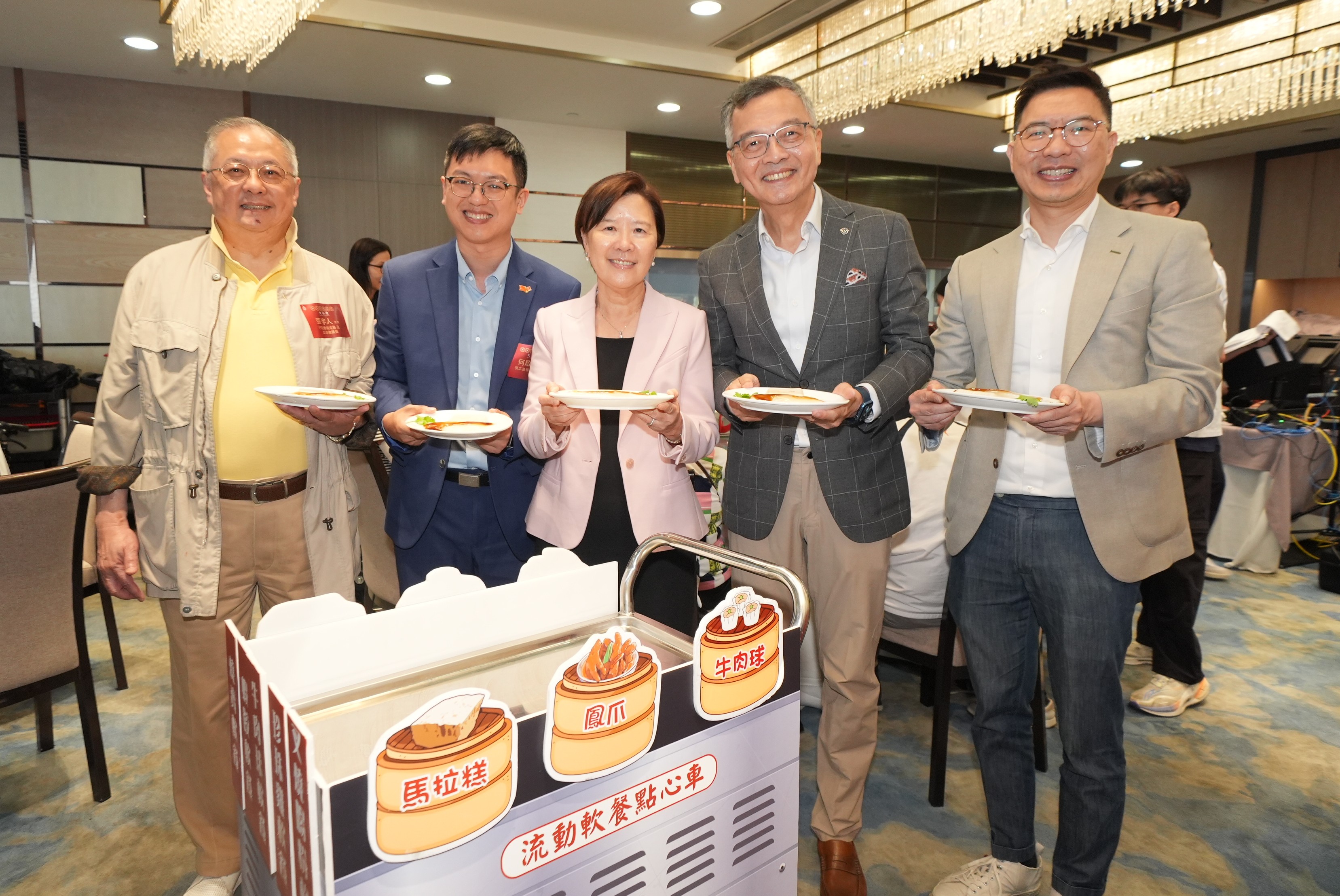 舊式點心車今日重現香港科技大學（科大）校園的中式茶樓內，上面盛載著精緻軟餐，由行政會議成員暨基督教靈實協會行政總裁林正財醫生（右二）、行政會議成員暨立法會議員張宇人先生（左一）、勞工及福利局副局長何啟明先生（左二）、黃大仙民政事務專員胡鉅華先生（右一）及科大校長葉玉如教授（左三）帶領學生和教職員義工隊，共同為長者送上叉燒腸粉及蘿蔔糕。 