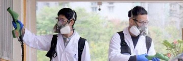 2 people in masks disinfecting a campus hallway