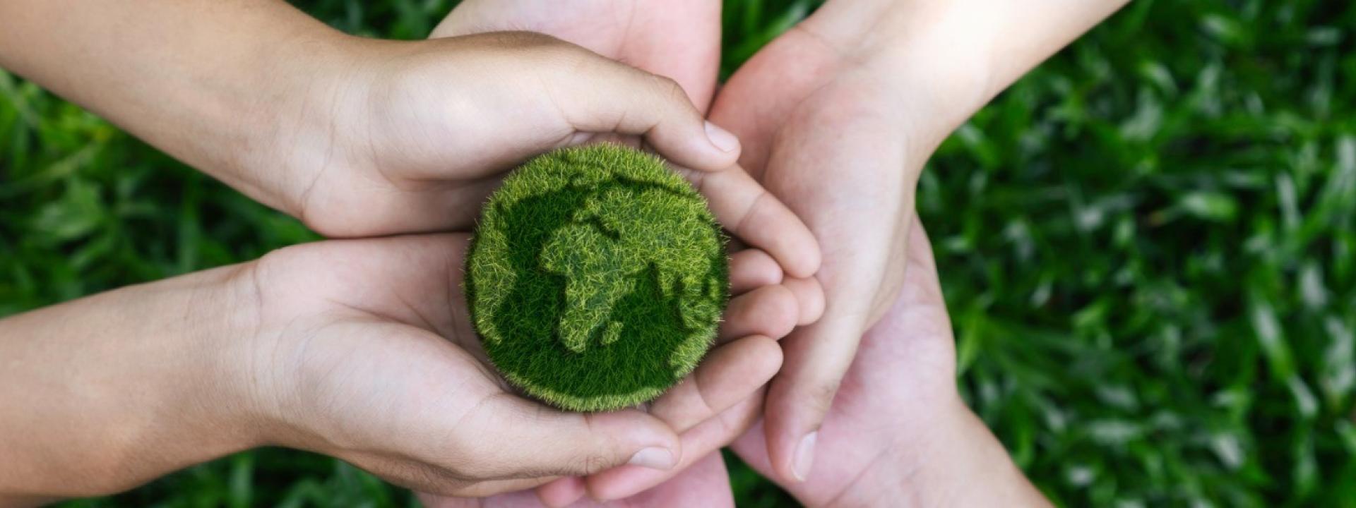 Hands holding an Earh-shaped ball of grass